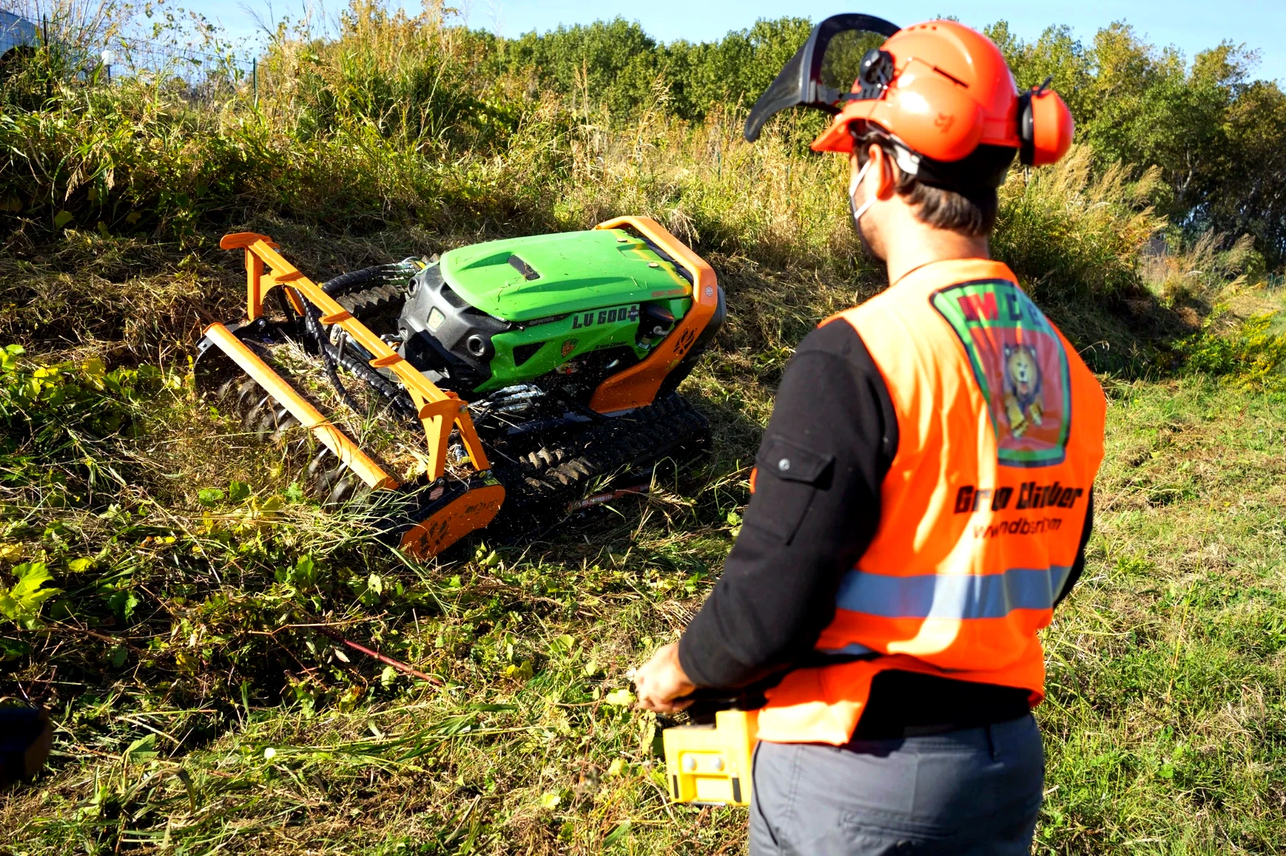 Operator controlling a remote tracked vegetation management machine from a distance